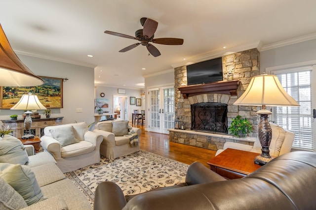 living room featuring ceiling fan, a fireplace, crown molding, and hardwood / wood-style flooring