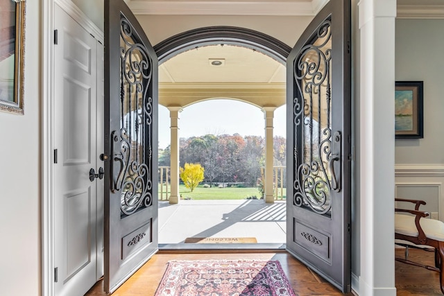 entryway with wood-type flooring and crown molding