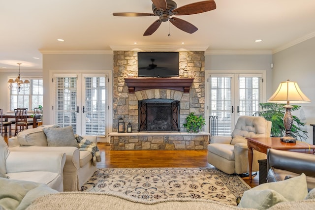 living room featuring a stone fireplace, french doors, ornamental molding, and hardwood / wood-style flooring