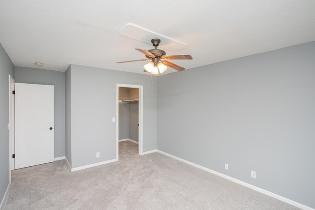 unfurnished bedroom with ceiling fan, light colored carpet, a walk in closet, and a closet