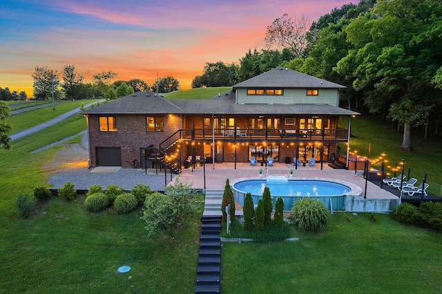 back house at dusk featuring a pool side deck, a yard, a patio area, and a garage