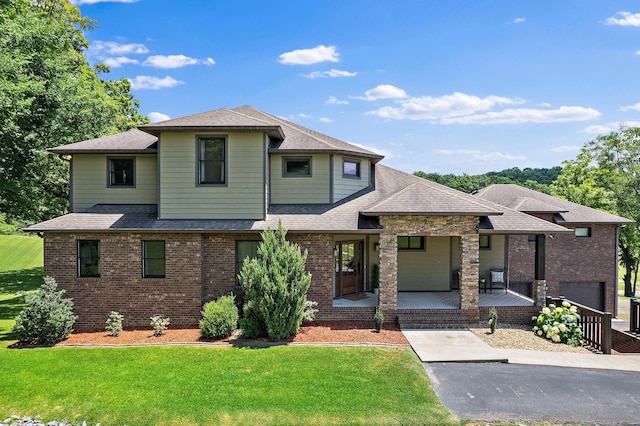 view of front of house featuring a front yard, a porch, and a garage