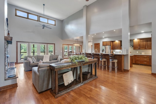 living room with a high ceiling, light wood-type flooring, and ceiling fan