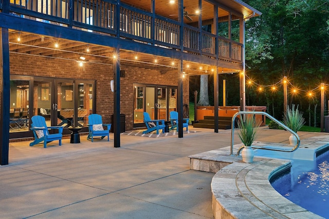 view of patio featuring a pool with hot tub, ceiling fan, and a balcony