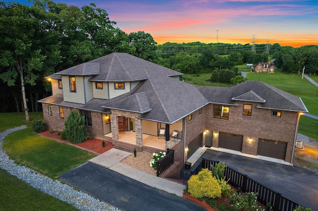 view of front of house featuring a garage, a lawn, and a porch