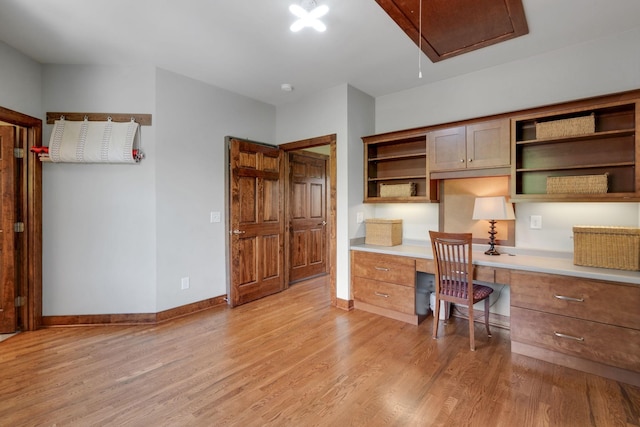 home office with built in desk and light hardwood / wood-style flooring