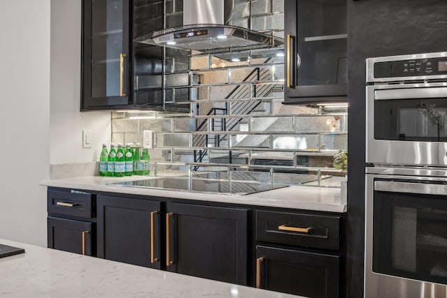 kitchen with light stone countertops, stainless steel double oven, island exhaust hood, decorative backsplash, and black electric stovetop