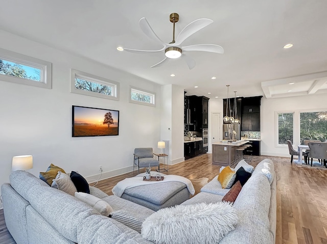 living room with ceiling fan, beam ceiling, light hardwood / wood-style floors, and coffered ceiling