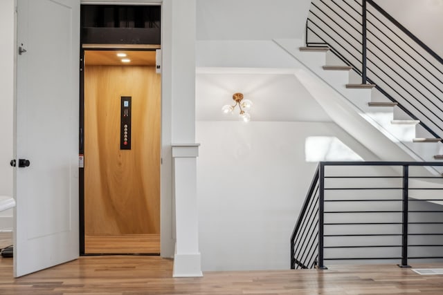 stairs with elevator and hardwood / wood-style floors