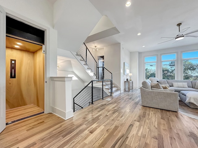 living room with light wood-type flooring, elevator, and ceiling fan