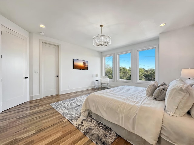 bedroom with hardwood / wood-style floors and a notable chandelier