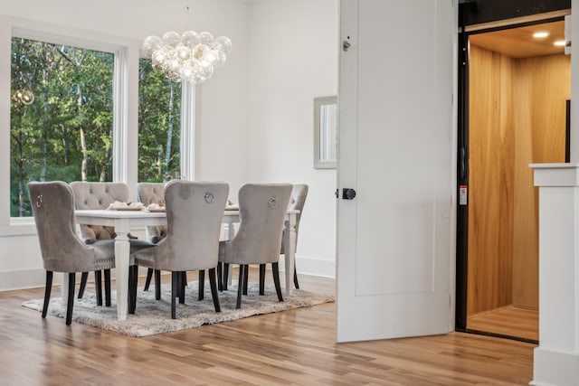 dining room with a chandelier, hardwood / wood-style floors, and elevator