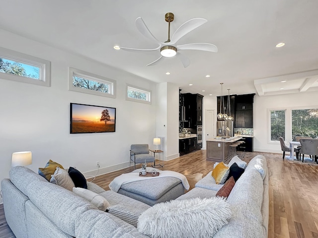 living room featuring beamed ceiling, ceiling fan, light wood-type flooring, and coffered ceiling