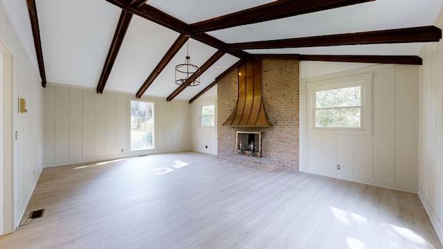 unfurnished living room with a notable chandelier, vaulted ceiling with beams, light wood-type flooring, and a fireplace