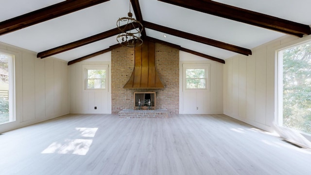 unfurnished living room with a fireplace, light wood-type flooring, lofted ceiling with beams, and a healthy amount of sunlight