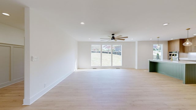 unfurnished living room with ceiling fan and light hardwood / wood-style flooring