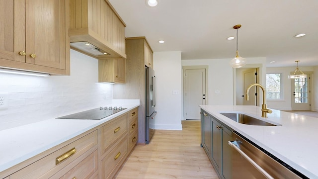 kitchen featuring light brown cabinets, sink, light hardwood / wood-style flooring, appliances with stainless steel finishes, and decorative light fixtures