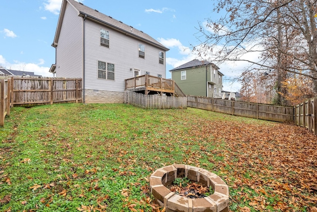 rear view of house with an outdoor fire pit, a lawn, and a deck