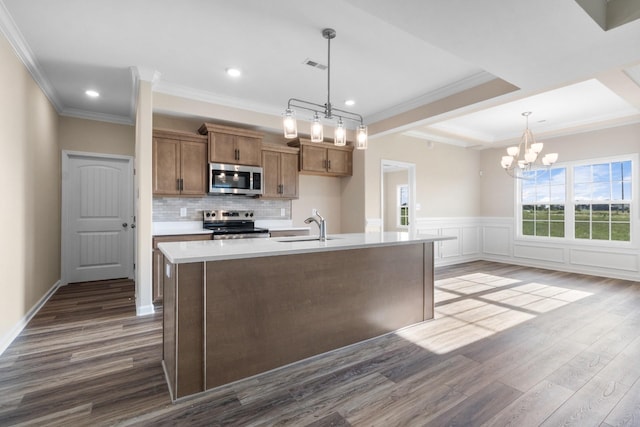 kitchen with decorative light fixtures, sink, stainless steel appliances, and a kitchen island with sink