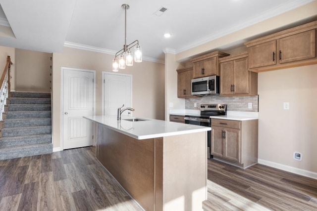 kitchen with stainless steel appliances, dark wood-type flooring, sink, pendant lighting, and a center island with sink