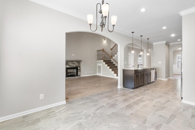 kitchen featuring sink, hanging light fixtures, a notable chandelier, a fireplace, and ornamental molding