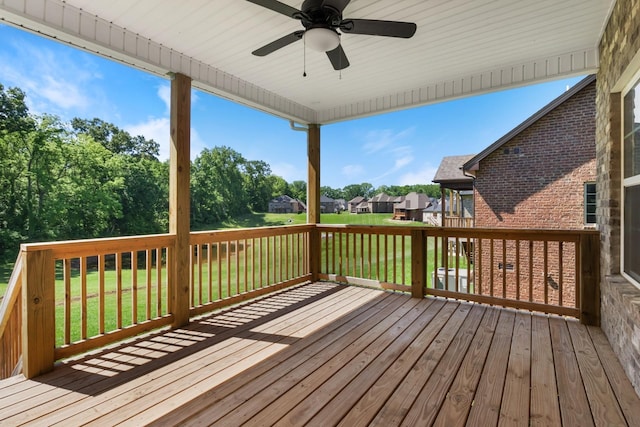 wooden terrace featuring ceiling fan and a yard