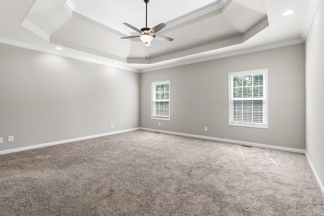 carpeted empty room with a raised ceiling, ceiling fan, and ornamental molding