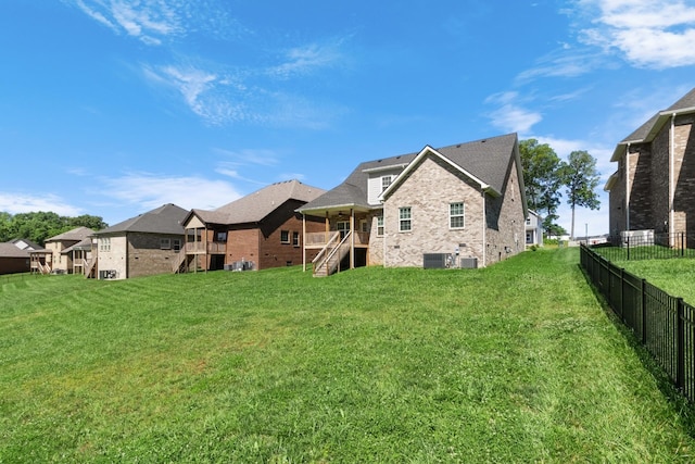 rear view of property featuring a lawn and central air condition unit