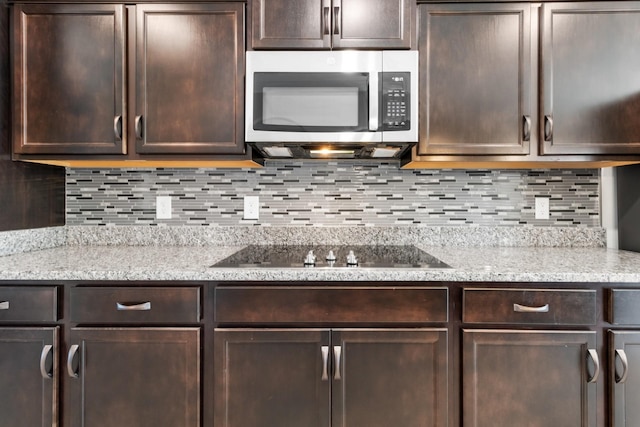 kitchen with dark brown cabinets, tasteful backsplash, light stone counters, and black electric cooktop