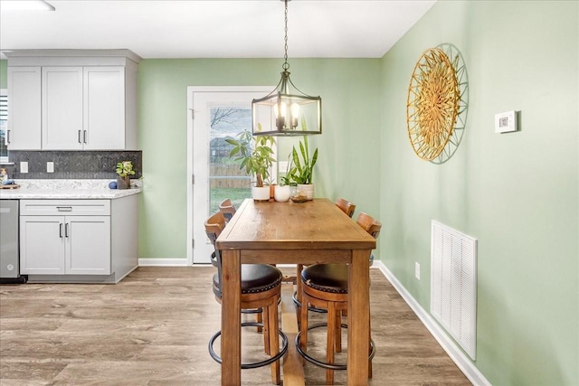 dining space featuring light wood-type flooring and an inviting chandelier