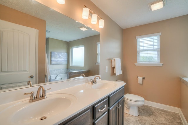 bathroom with plenty of natural light, vanity, a bath, and a textured ceiling