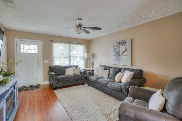 living room featuring ceiling fan, dark hardwood / wood-style flooring, and a textured ceiling