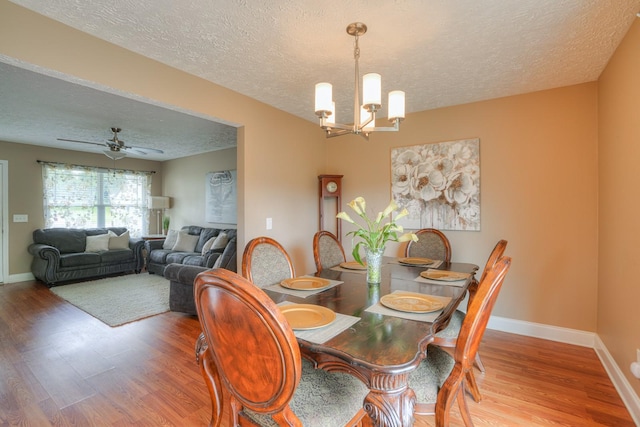 dining area with a textured ceiling, ceiling fan with notable chandelier, and hardwood / wood-style flooring