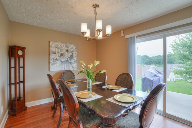 dining room featuring wood-type flooring, a textured ceiling, and an inviting chandelier