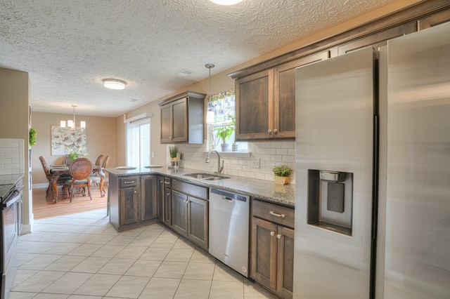 kitchen featuring light stone countertops, sink, stainless steel appliances, pendant lighting, and decorative backsplash