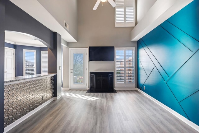 unfurnished living room featuring hardwood / wood-style flooring, ceiling fan, and a towering ceiling