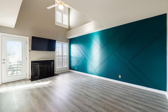 unfurnished living room featuring hardwood / wood-style floors, a towering ceiling, and ceiling fan