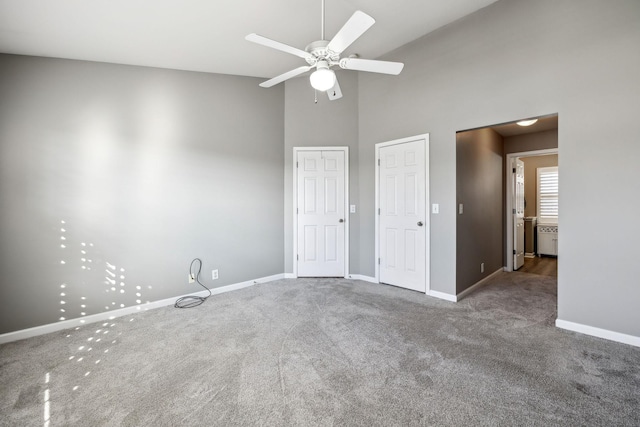 unfurnished bedroom with multiple closets, radiator, high vaulted ceiling, and carpet