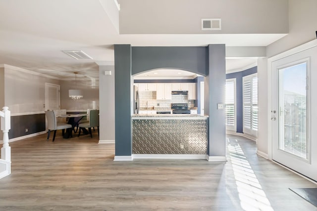 kitchen with black electric range oven, decorative backsplash, stainless steel fridge, and ornamental molding