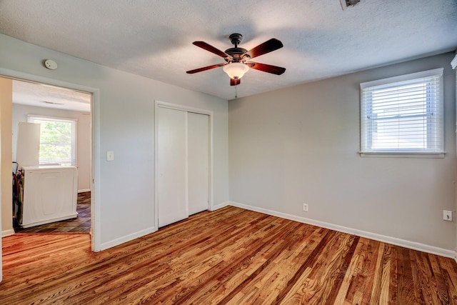 unfurnished bedroom with ceiling fan, wood-type flooring, a textured ceiling, and multiple windows