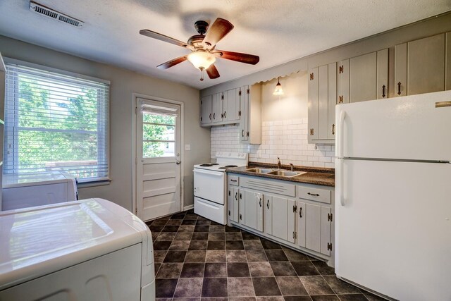 kitchen with white appliances, sink, ceiling fan, tasteful backsplash, and washer / dryer