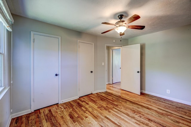 unfurnished bedroom featuring ceiling fan, light hardwood / wood-style floors, and a textured ceiling