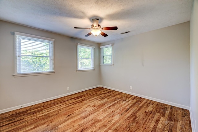 empty room featuring ceiling fan, wood-type flooring, and a textured ceiling