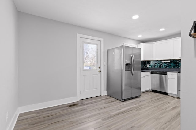 kitchen with white cabinets, light hardwood / wood-style floors, backsplash, and appliances with stainless steel finishes