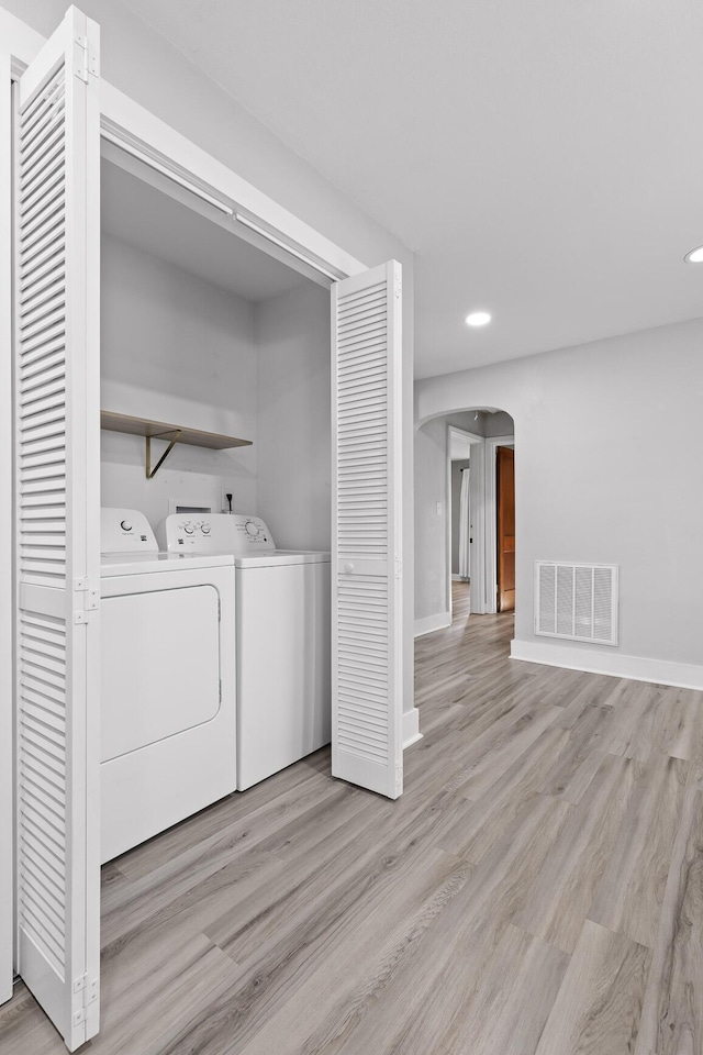 clothes washing area featuring light hardwood / wood-style flooring and washing machine and clothes dryer