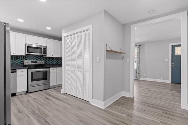 kitchen featuring decorative backsplash, appliances with stainless steel finishes, light hardwood / wood-style floors, and white cabinetry