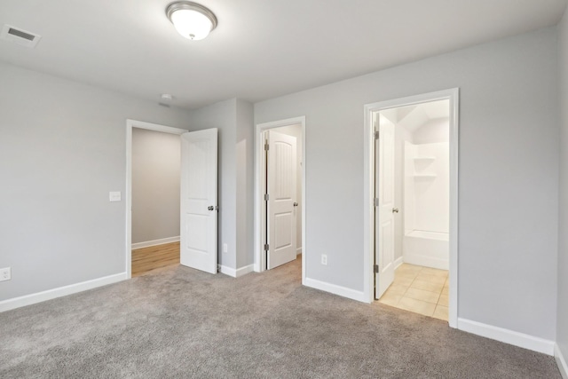 unfurnished bedroom featuring connected bathroom and light colored carpet