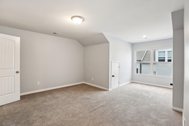 bonus room with lofted ceiling and light carpet