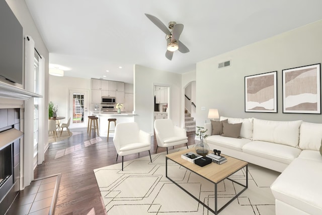 living room featuring hardwood / wood-style floors, ceiling fan, and a fireplace