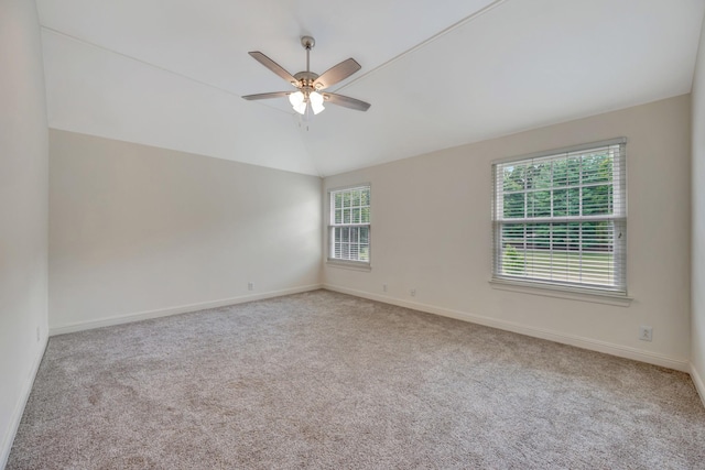 spare room featuring ceiling fan, a healthy amount of sunlight, light carpet, and vaulted ceiling